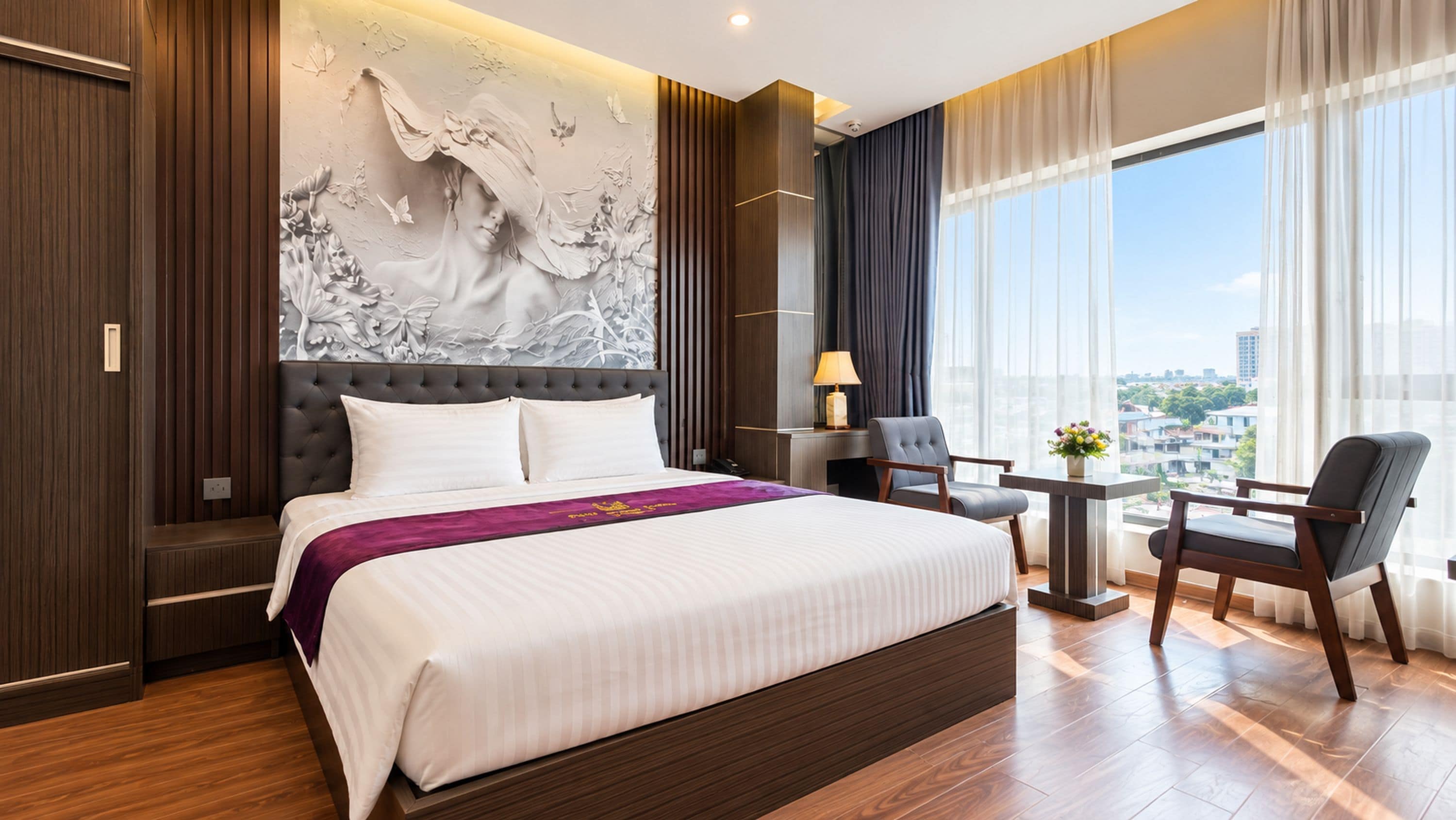 A hotel room with a large bed, a desk, and a view of the city.
