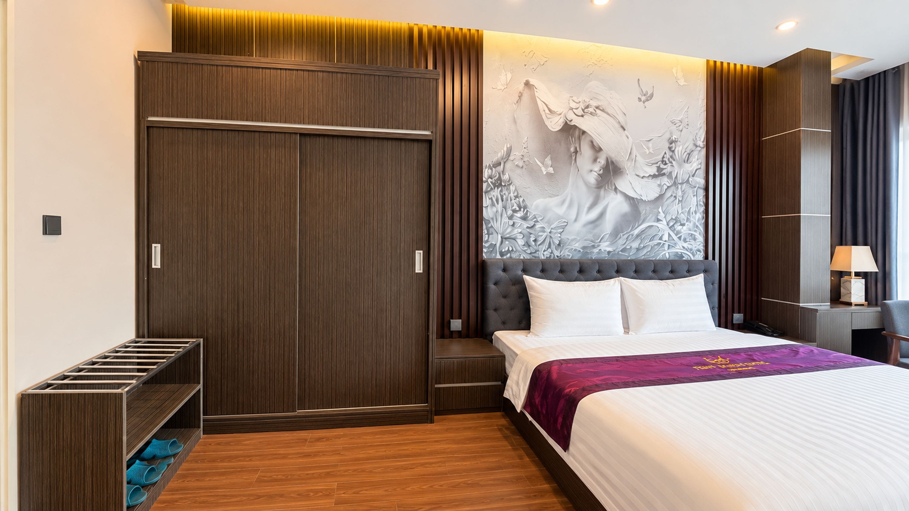 Ein Hotelzimmer mit einem großen Bett, einem Kleiderschrank, Wandmalerei und einem Nachttisch.
