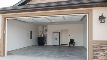 A garage with a covered entrance, a door, and a chair.