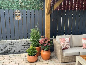 Ein Patio mit Korbsessel, Blumentöpfen und einem Holzzaun mit einem Schild.