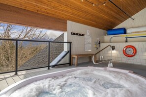 A hot tub with a wooden deck and a view of mountains. - Mountains Plenty | Luxury Hot Tub and Sauna (Canmore)
