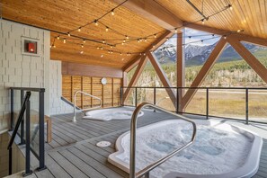 A hot tub area with wooden flooring and a view of mountains. - Mountains Plenty | Luxury Hot Tub and Sauna (Canmore)
