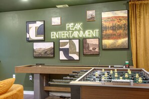 Une pièce avec une table de baby-foot, un canapé et plusieurs tableaux encadrés accrochés au mur.