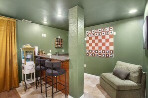 Une pièce comprenant un coin bar, un mur décoré de motifs à carreaux et un canapé.