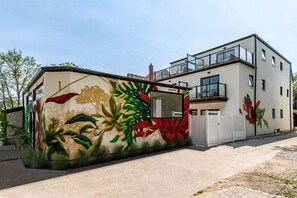 Um edifício moderno com um grande mural de plantas tropicais em sua fachada.
