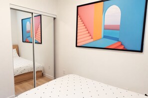Quarto com cama, guarda-roupa e uma grande moldura na parede.