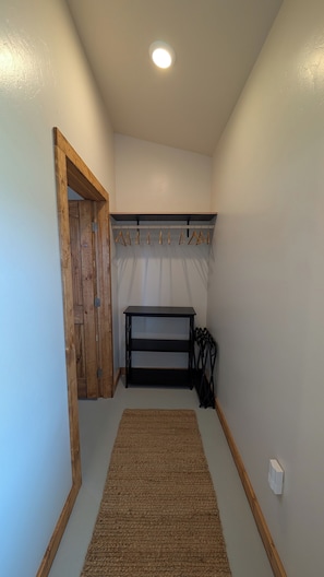 A narrow hallway with a wooden door, a black bench, and a hanging coat rack. - Amazing Views b/t Yellowstone and Livingston, Quiet & Private (Livingston)