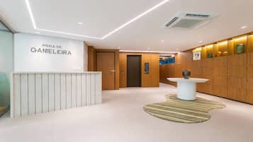 A reception area with a reception desk, a wall-mounted sign, a wooden panel wall, a patterned rug, and a wall-mounted air conditioning unit.