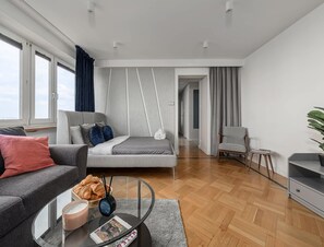 Un dormitorio moderno con cama, sofá, una mesita de centro y vistas a un pasillo.