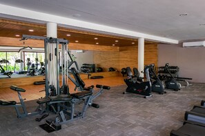 A gym with cardio machines, weightlifting equipment, and a mirror wall. - Kovay Gardens 2BR by Monyxbnb (La Cruz de Huanacaxtle)