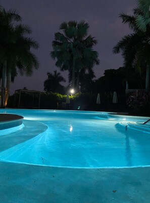 A swimming pool with a circular shape and a surrounding area with palm trees and umbrellas. - Kovay Gardens 2BR by Monyxbnb (La Cruz de Huanacaxtle)