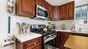 A kitchen with wooden cabinets, a stainless steel stove, and a microwave. - Casa Marlow by Avantstay Urban San Diego Retreat Near Balboa Park + Beaches + Downtown (San Diego)