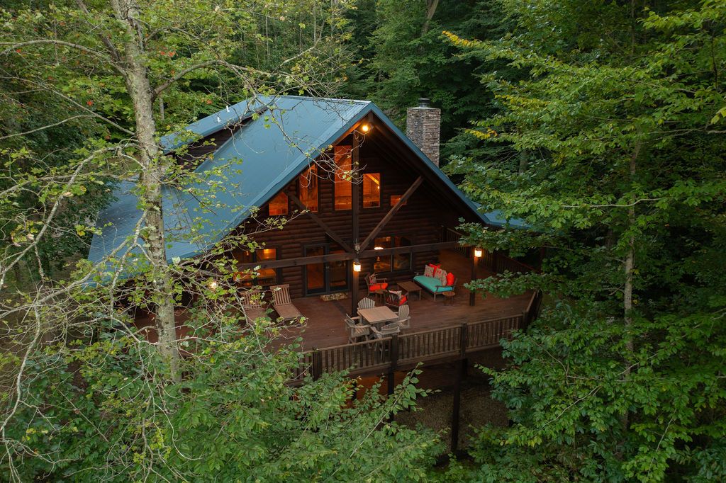 A cabin with a deck, surrounded by trees.