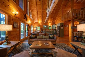 A spacious wooden cabin interior with a large living area, a dining table, and a kitchen. - Luna Moth | Hocking Hills, Firepit, Pool Table (Logan)