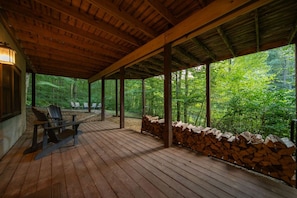 A covered wooden deck with Adirondack chairs, a fire pit, and a stone wall. - Luna Moth | Hocking Hills, Firepit, Pool Table (Logan)