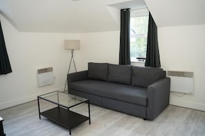 A modern living room with a gray sofa, a glass coffee table, and a floor lamp. - Jacobs court 47 (Crawley)
