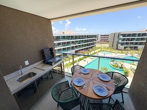A balcony with a dining table set for four, a laptop, and a sink. - Beach Class Solare Muro Alto (Ipojuca)