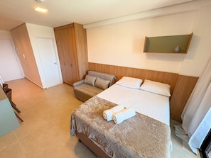 A hotel room with a bed, a sofa, a wardrobe, and a small table. - Beach Class Solare Muro Alto (Ipojuca)