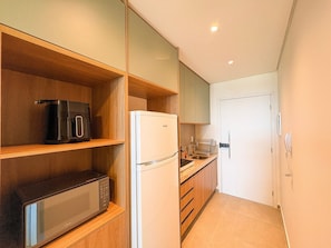 A compact kitchen with a microwave, a coffee maker, and a refrigerator. - Beach Class Solare Muro Alto (Ipojuca)