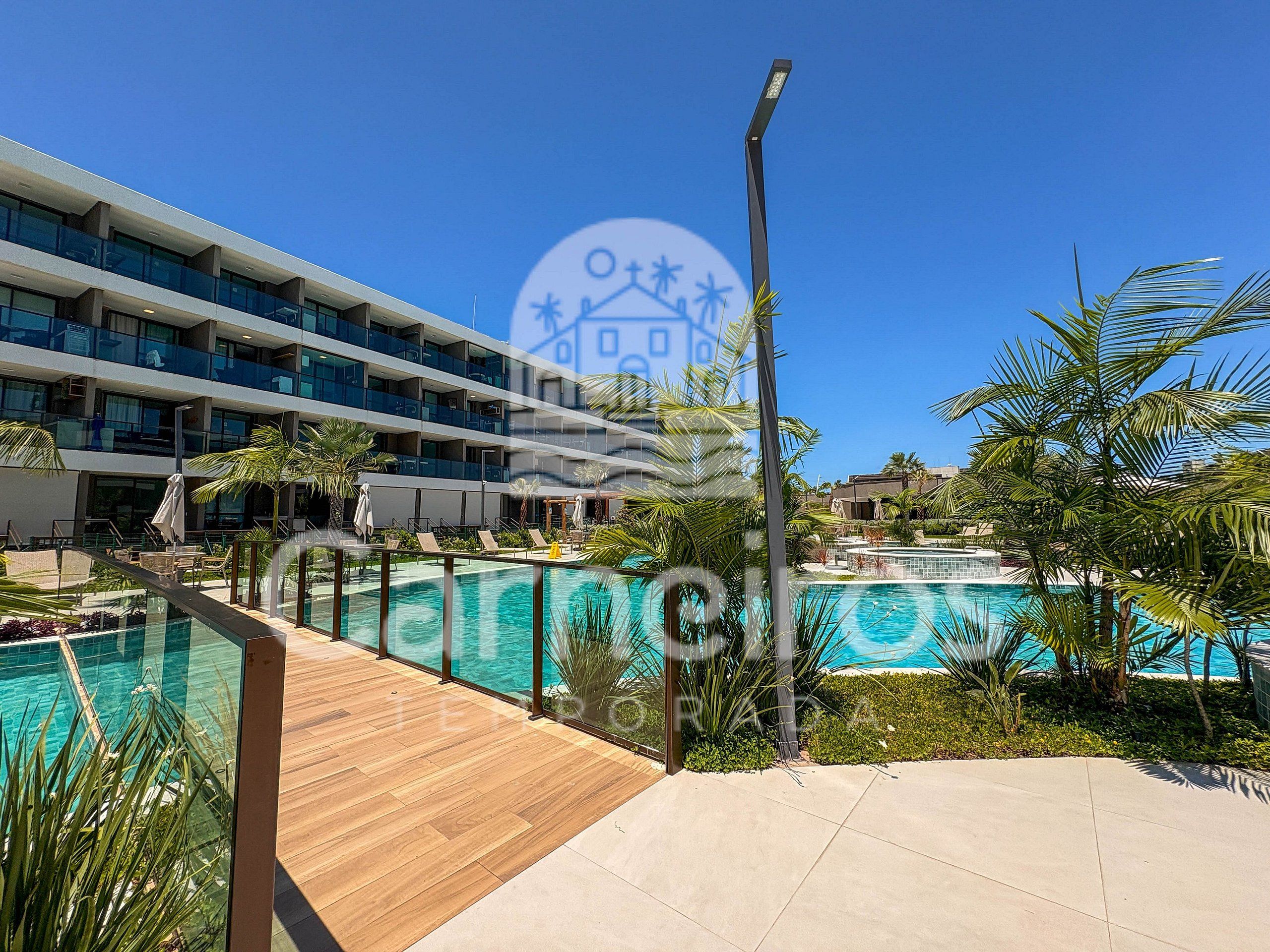 A hotel with a pool, outdoor seating, and a clear blue sky.
