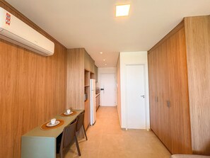 A hallway with wooden paneling, a kitchenette, and a dining area with a table and chairs. - Beach Class Solare Muro Alto (Ipojuca)