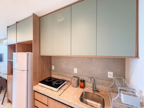 A modern kitchen with a built-in stove, a sink, and wooden cabinets. - Beach Class Solare Muro Alto (Ipojuca)