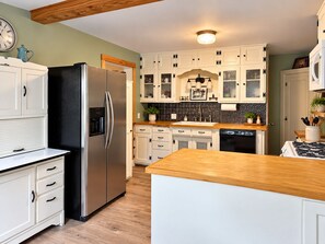 Eine moderne Küche mit weißen Schränken, Edelstahlgeräten und einer Holzausziehtafel.