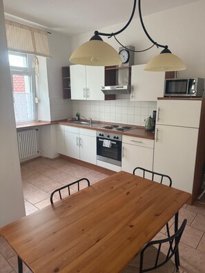 Une cuisine de taille réduite avec une table en bois, des placards blancs, une cuisinière et un four à micro-ondes.