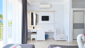 Un dormitori modern amb un escriptori blanc, una televisió de pantalla plana, un petit tamboret i un safata de brossa blau.