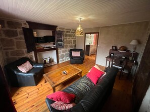 Ein Wohnzimmer mit Steinwand, einer schwarzen Ledersofa, einem Holztisch und einem schwarzen Ledersessel.