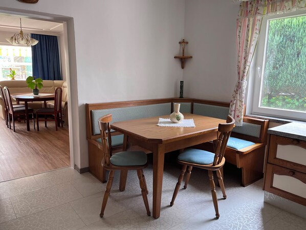 A dining area with a wooden table and chairs, a bench, and a view of greenery through a window. - New Listing (Thaling)