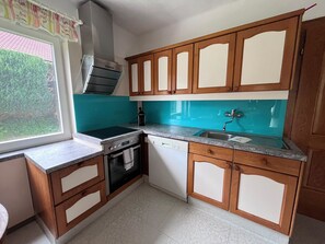 A kitchen with wooden cabinets, a built-in oven, a dishwasher, and a window with a view of greenery. - New Listing (Thaling)