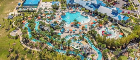 An aerial view of a resort with multiple swimming pools, palm trees, and a large building with a blue roof.