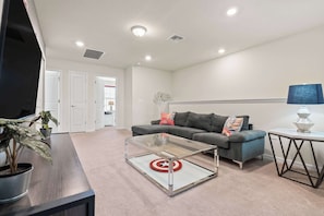A modern living room with a sofa, a coffee table, and a TV. - Mickey Magic and Harry Potter Pool Retreat (Davenport)