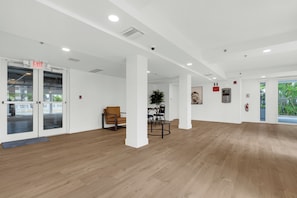 Un interior amplio con piso de madera, paredes blancas y una puerta de vidrio con la indicación 'EXIT'.