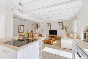 A modern kitchen with a central island, a dining area with a sofa, and a TV. - Casa dos Pombinhos in Porches (Lagoa)