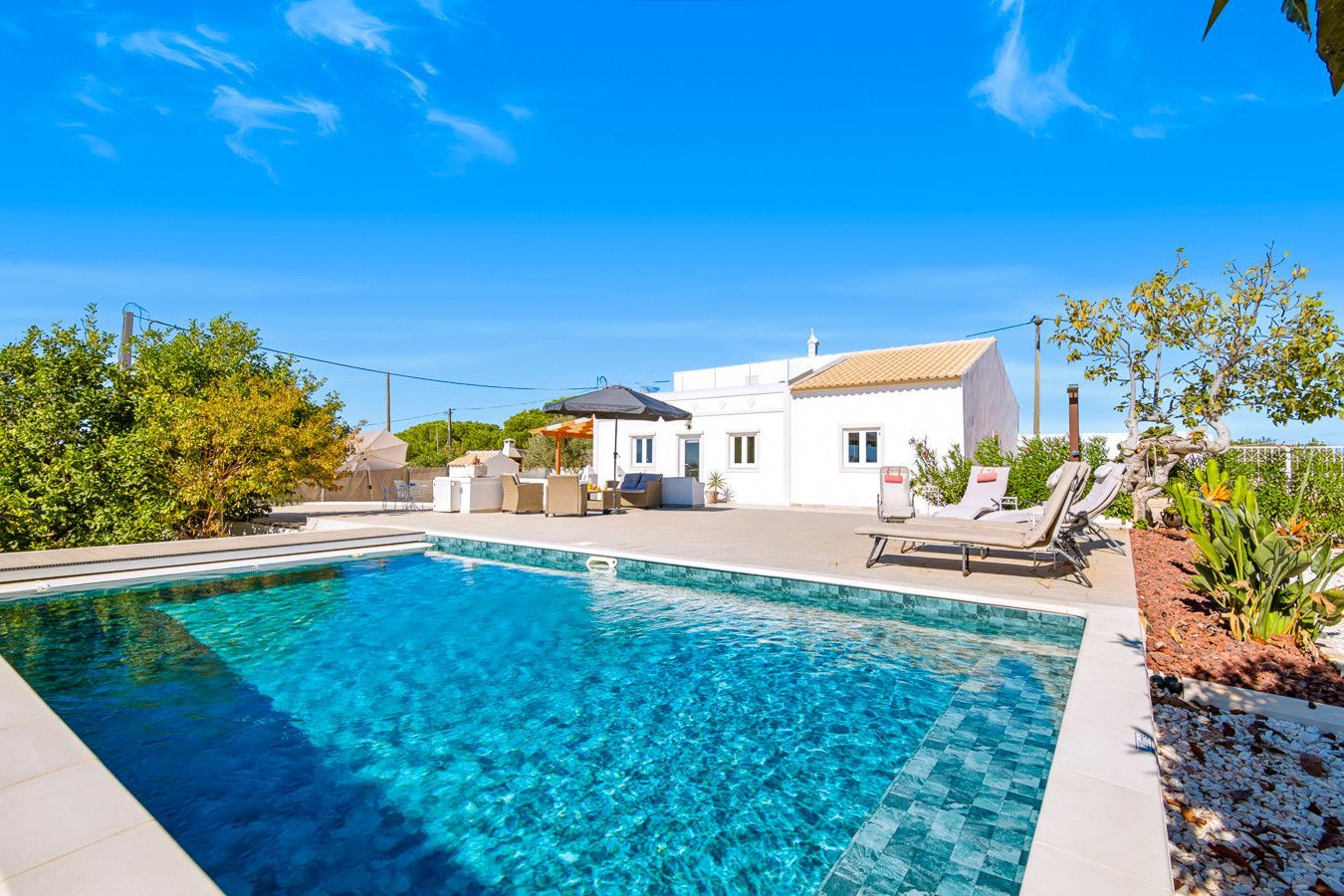 Una piscina con sillones de descanso y un patio.