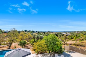 A pool area with a view of a landscape including trees and distant buildings. - Casa dos Pombinhos in Porches (Lagoa)