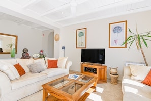 A living room with a sofa, coffee table, TV, and decorative items. - Casa dos Pombinhos in Porches (Lagoa)