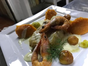 Un plato de comida con camarones, papas y una guarnición.