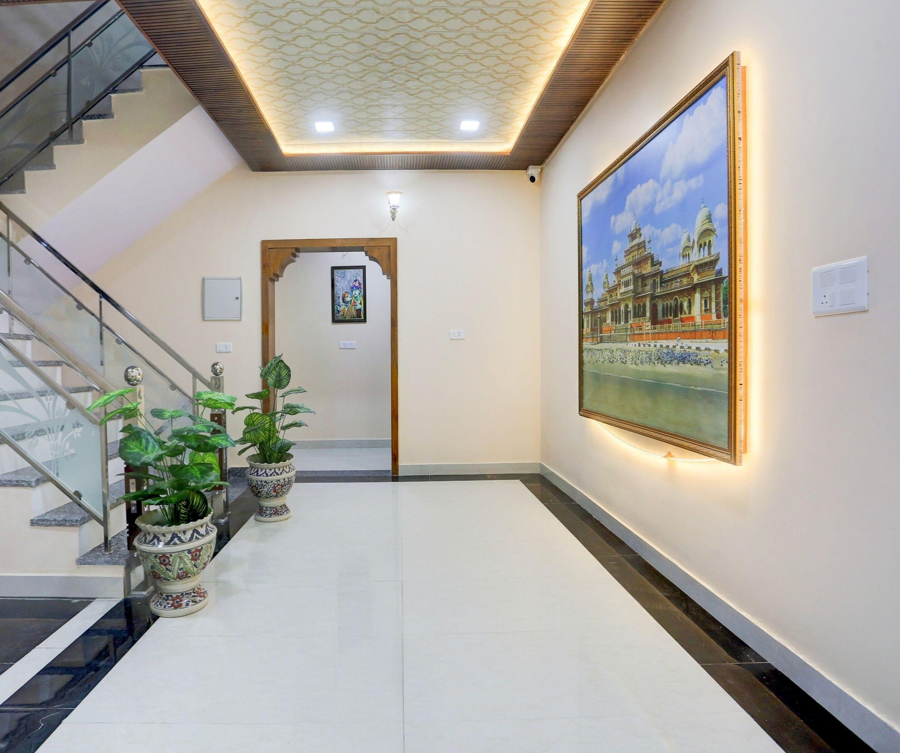 A hallway with a staircase, a framed painting, and potted plants.