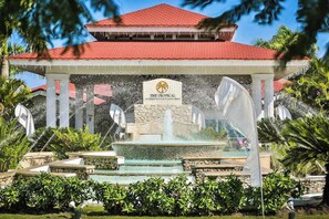 A tropical resort with a water fountain, a red-roofed pavilion, and lush greenery. - Junior Suite – Beachfront Escape on Cofresí Beach (Puerto Plata)