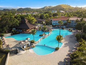 A resort with multiple swimming pools, palm trees, and a mountainous backdrop. - Junior Suite – Beachfront Escape on Cofresí Beach (Puerto Plata)
