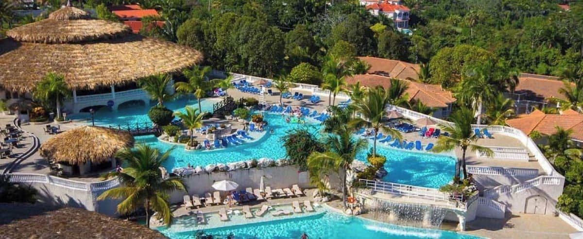 A resort with multiple swimming pools, lounge areas, and thatched-roof structures.