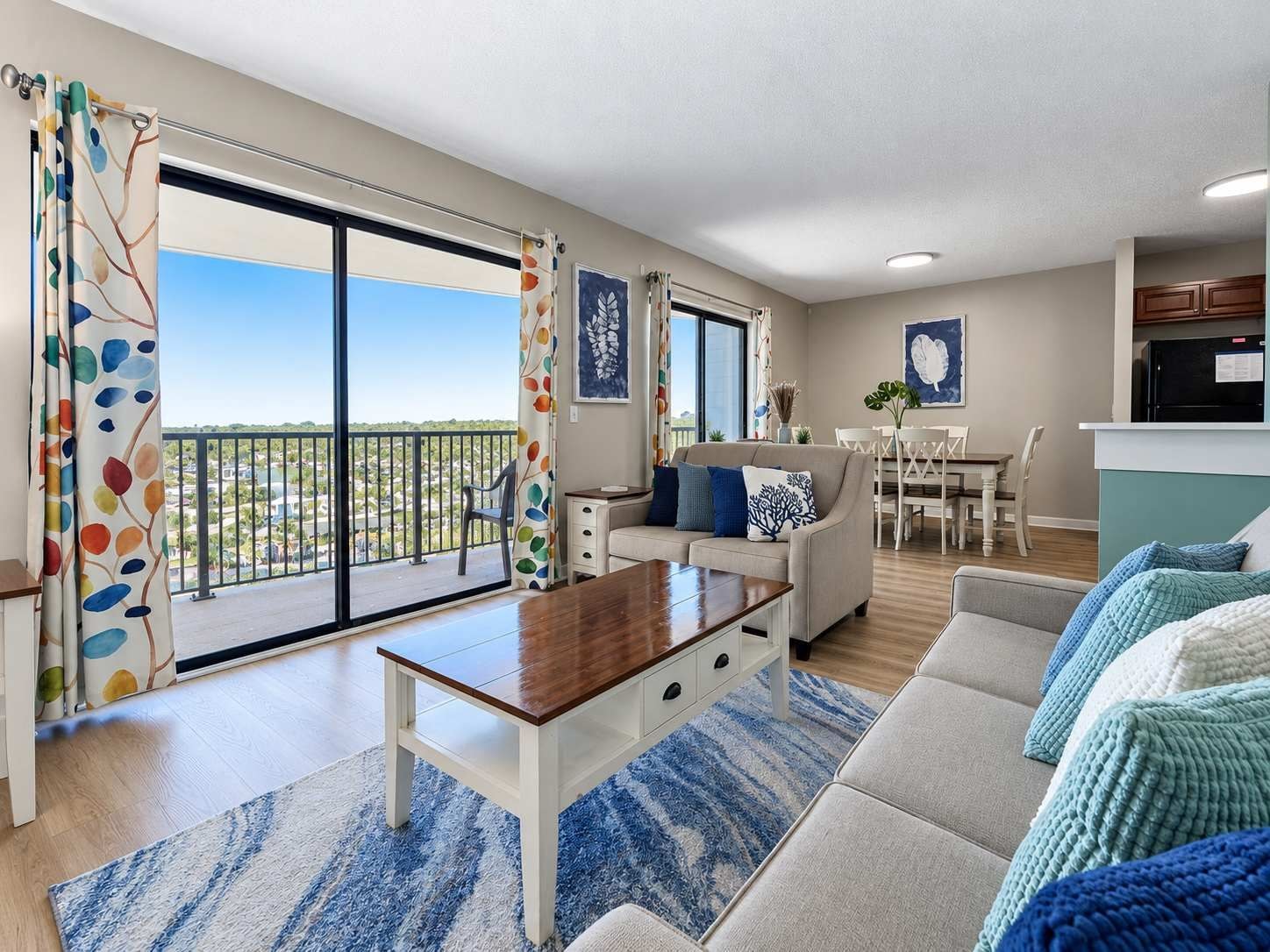 A modern living room with a sofa, coffee table, and a view of the outdoors through large sliding doors.