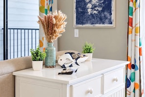 A white dresser with a vase of dried pampas grass, two small potted plants, and a decorative fish sculpture. - Myrtle Beach Resort B-526 with Endless Myrtle Beach Adventures! (Myrtle Beach)