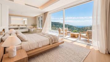 Une chambre moderne avec un grand lit, des tables de chevet, une commode et une vue sur un paysage montagneux grâce à de grandes fenêtres du sol au plafond.