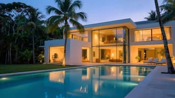 Une maison moderne à deux étages avec une piscine, entourée de palmiers.