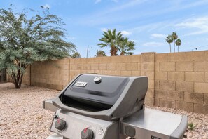 An outdoor grill with a digital display, set against a backdrop of a clear sky and a brick wall. - The Gila House | Pool in Downtown Chandler (Chandler)