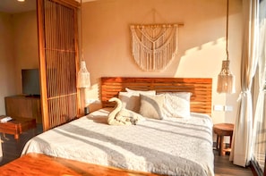 A bedroom with a wooden headboard, a macrame wall hanging, a swan decoration, and a television on a wooden cabinet. - Estudio arm  nico y esencia caribe  a  Cerca del mar (Playa del Carmen)